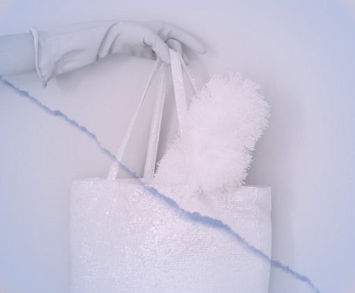 Photo d'une main gantée tenant un sca rempli d'une balayette pour illustrer cet article sur les produits d'entretien indispensables
