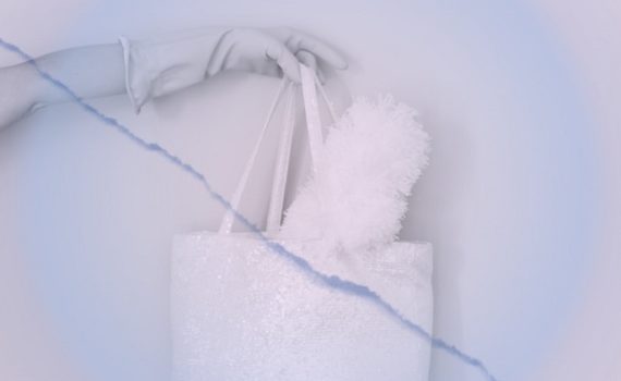 Photo d'une main gantée tenant un sca rempli d'une balayette pour illustrer cet article sur les produits d'entretien indispensables
