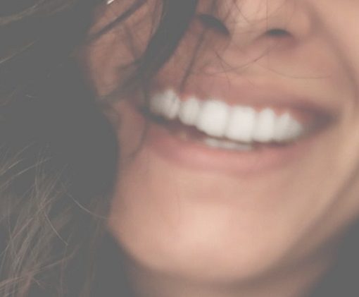 Photo d'une femme qui sourit pour illustrer cet article sur les produits essentiels pour l'hygiène des dents