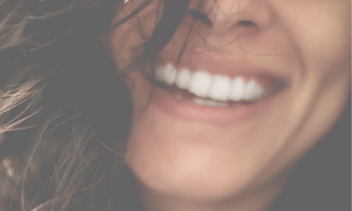 Photo d'une femme qui sourit pour illustrer cet article sur les produits essentiels pour l'hygiène des dents