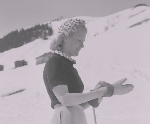 Photo vintage d'une femme à la montagne pour illustrer cet article sur les choses indispensables à ne surtout pas oublier d'emporter en voyage à la montagne en hiver quand il neige