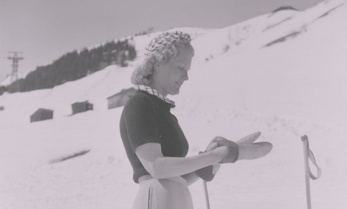 Photo vintage d'une femme à la montagne pour illustrer cet article sur les choses indispensables à ne surtout pas oublier d'emporter en voyage à la montagne en hiver quand il neige