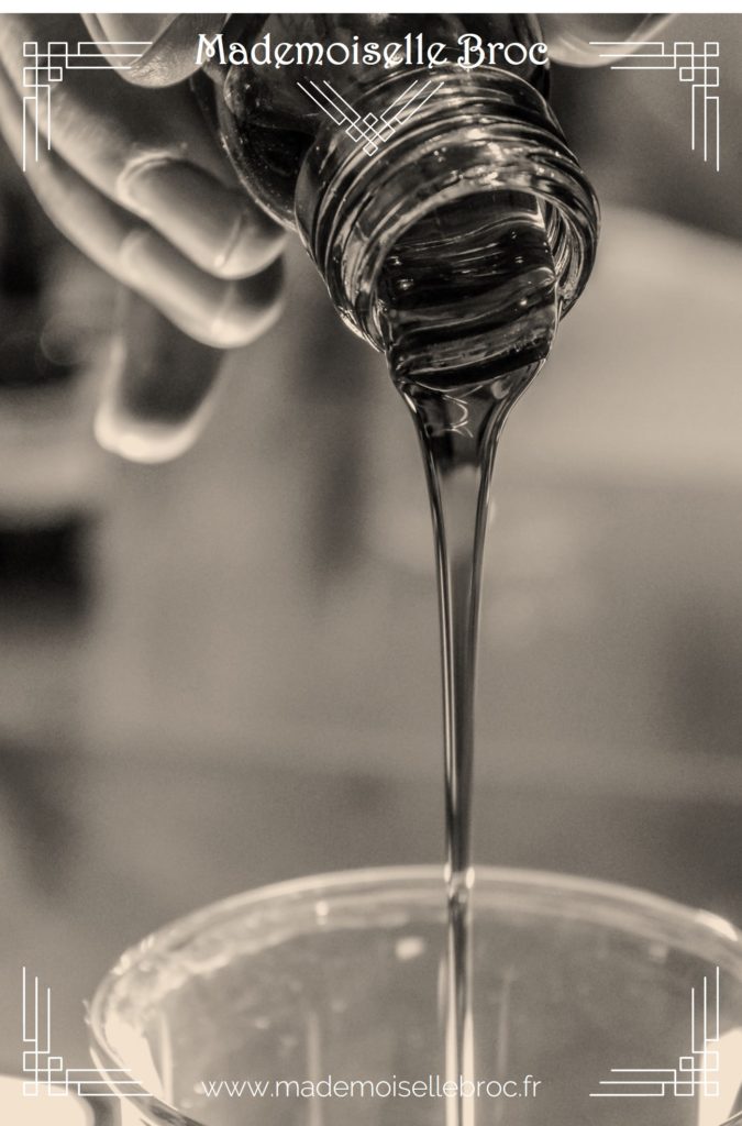 Photo d'une main versant un liquide dans un récipient en verre pour illustrer la fabrication de produits ménagers maison liquide coulant dans un bocal en verre