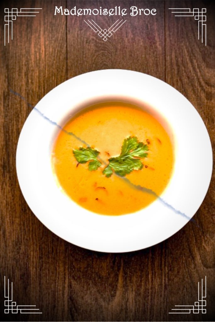 Photo d'une assiette remplie de soupe d'automne à la châtaigne et au potimarron posée sur une table en bois